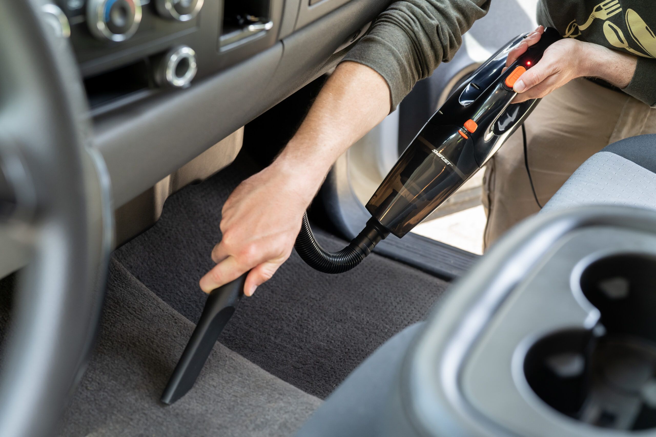 Using a handheld vacuum cleaner to clean the interior carpet o