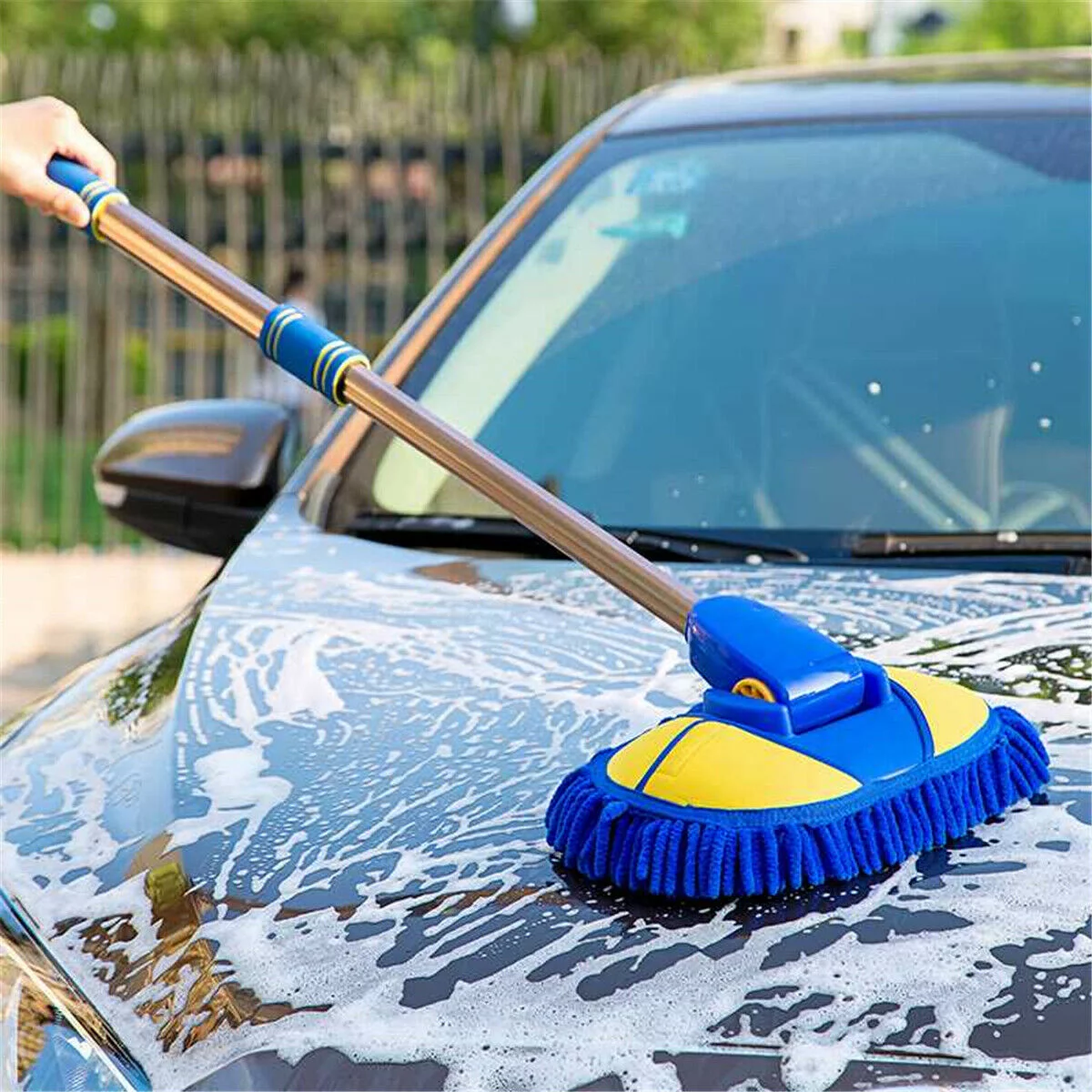 Car washing brush being used on a soapy car hood