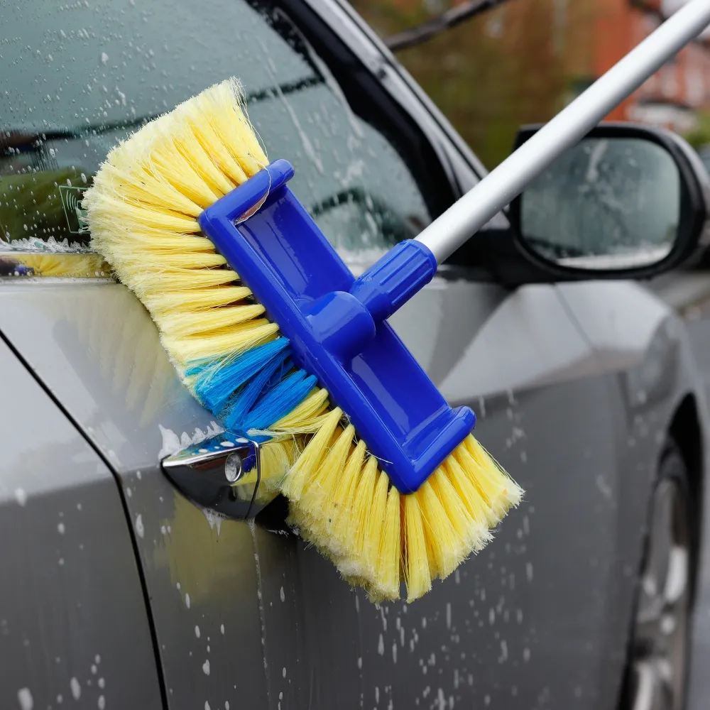 Car washing brush scrubbing a vehicle's door