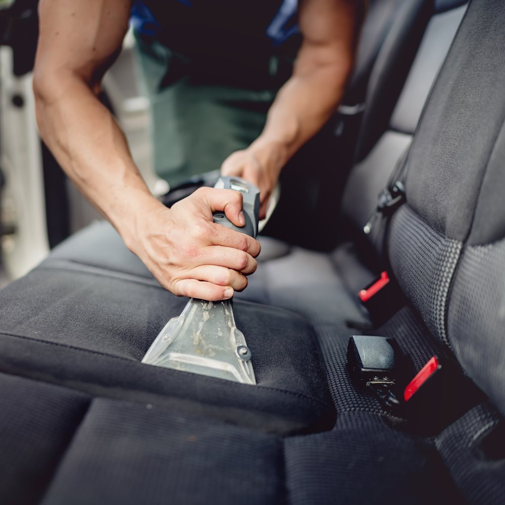 Professional car valet cleaning car seats with a vacuum, demonstrating the thoroughness of car valet services.