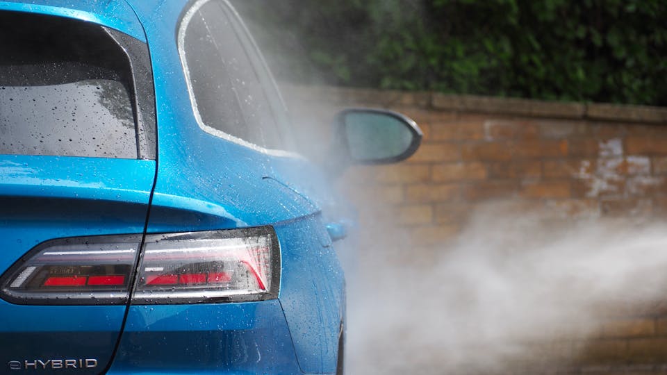 Blue car being washed with a high-pressure hose