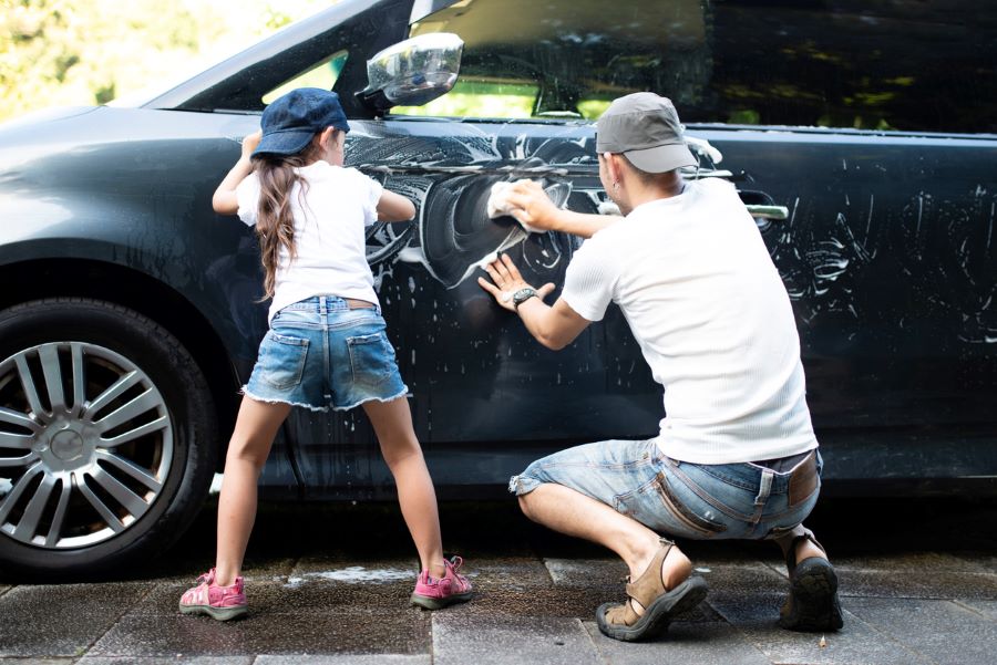 Father and daughter washing a car together at home