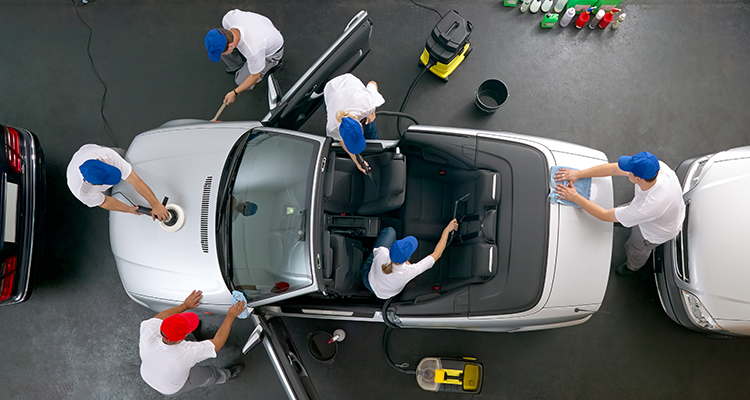 Professional team performing car detailing on a silver convertible, illustrating waterless cleaning versus traditional washing methods.