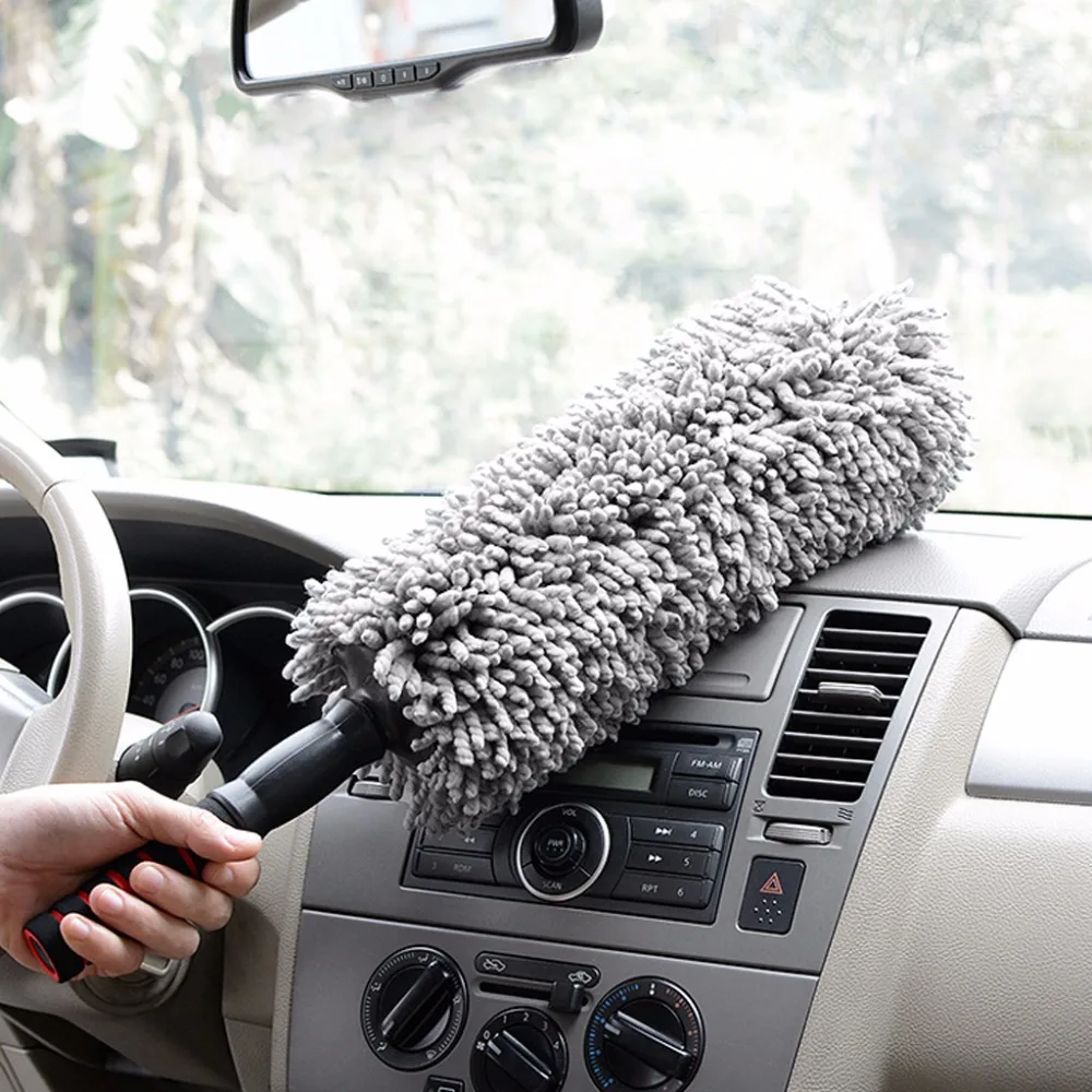 Hand using a microfiber duster to clean a car dashboard