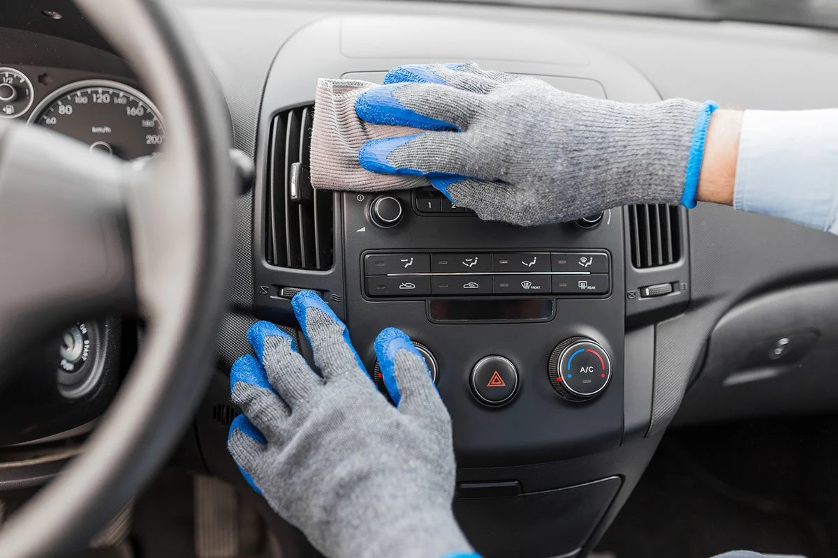 Person wearing gloves cleaning the car dashboard with a cloth during a full valet service