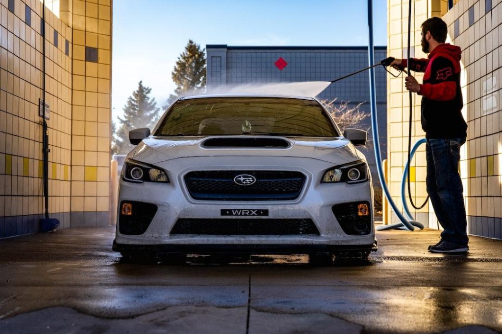 Man washing a white car at a self-service car wash station