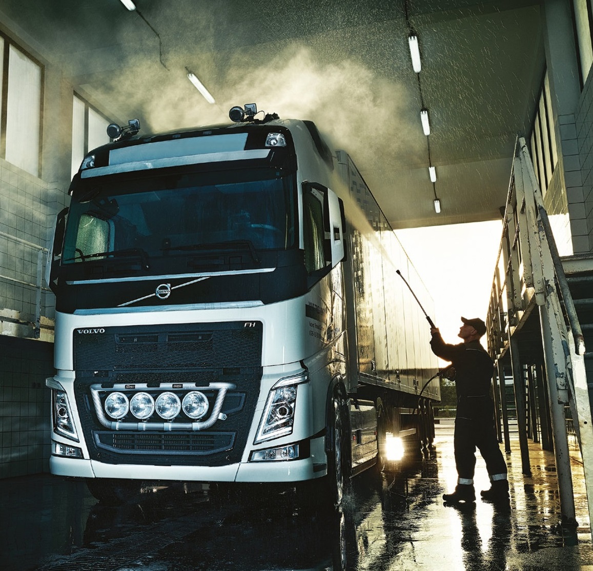 Professional truck wash service cleaning a large truck with a high-pressure washer.