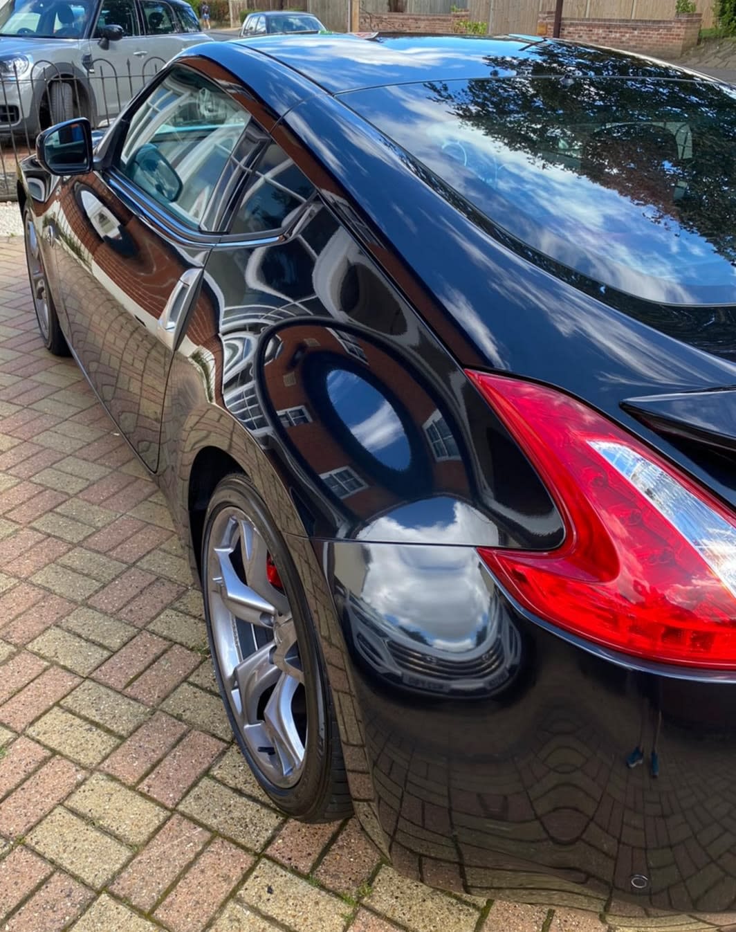 Shiny black car with a spotless exterior reflecting its surroundings, demonstrating the impact of regular washing on car resale value.