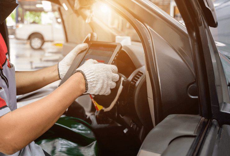 A technician is using a tablet to calculate the car valet services provided inside a vehicle.