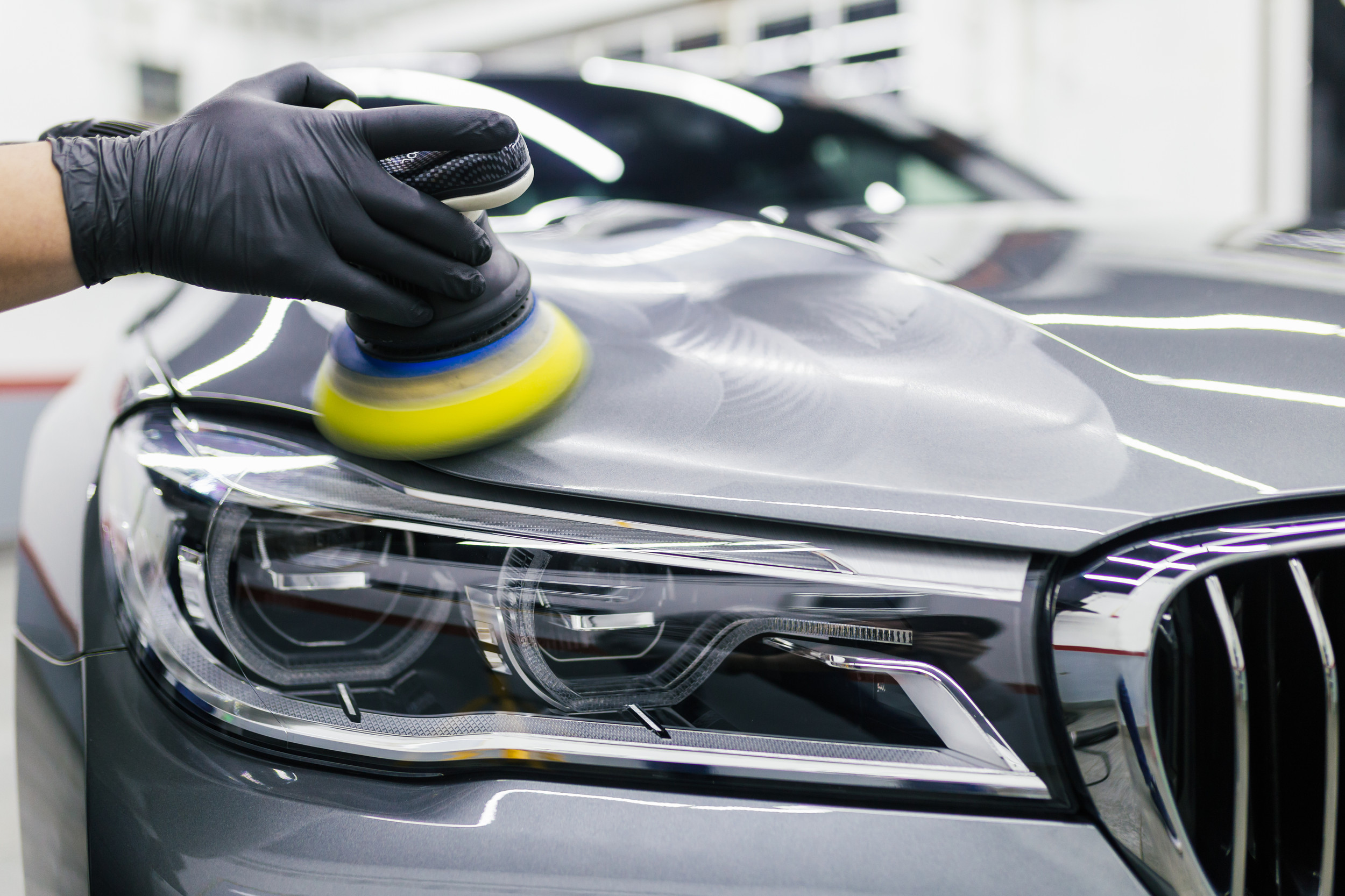 Close-up of a car being polished with a buffing tool, showcasing the application of ceramic coating for enhanced protection and shine.