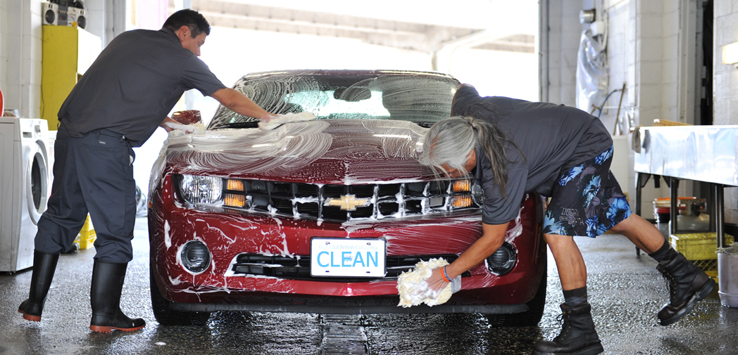 Two people hand-washing a red car, showcasing traditional car washing practices from around the world.