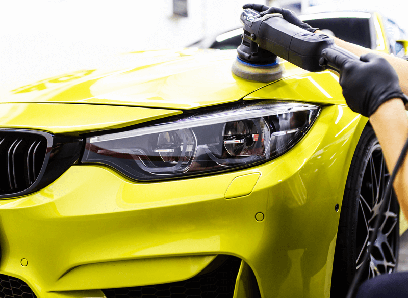 Professional polishing a luxury yellow car with a machine buffer, highlighting the benefits of high-end car valeting services.